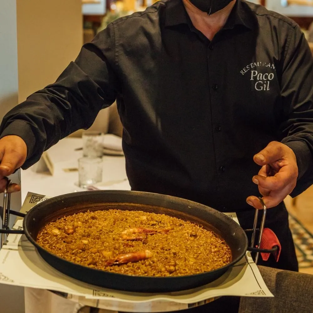 Camarero sirviendo un arroz recién hecho en paellera